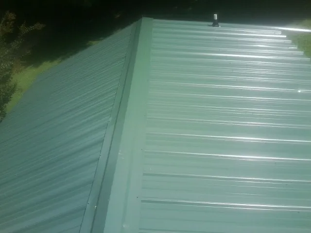 New green metal panels meeting at the ridge of a roof — Flat Roof Repair work by our crew in Vancouver