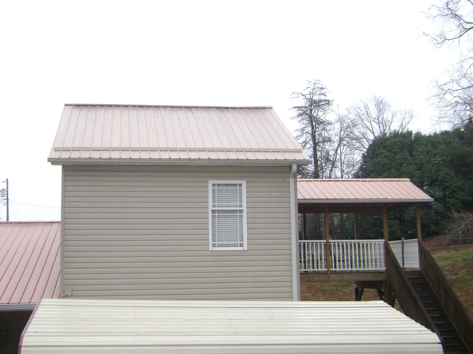 Tan metal roofs on a two story addition and attached porch, from a Roof Replacement job in Vancouver