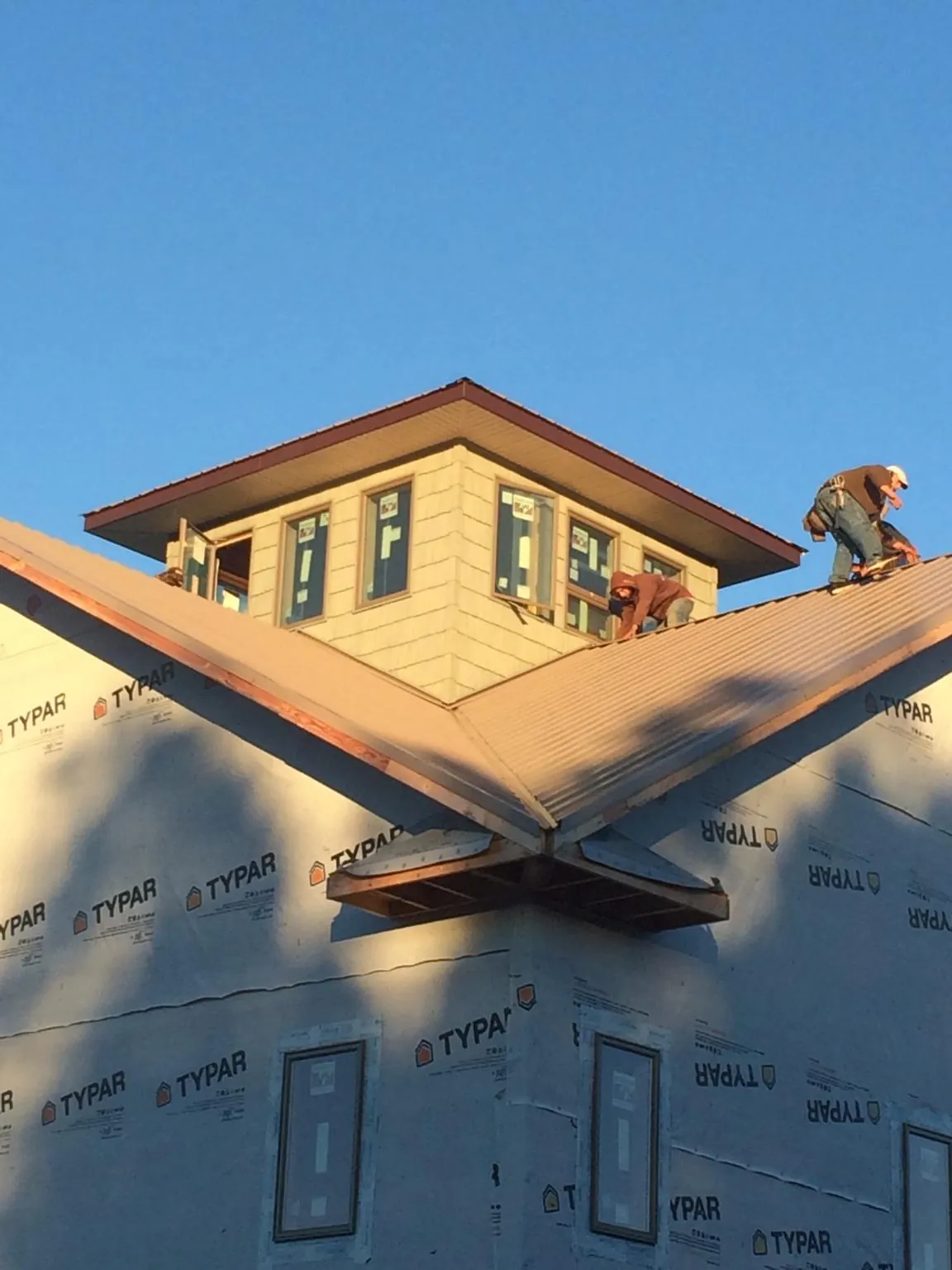 Roofers working around a rooftop cupola on a new metal roof at sunset — Roof Waterproofing in Vancouver by Roofing Brothers